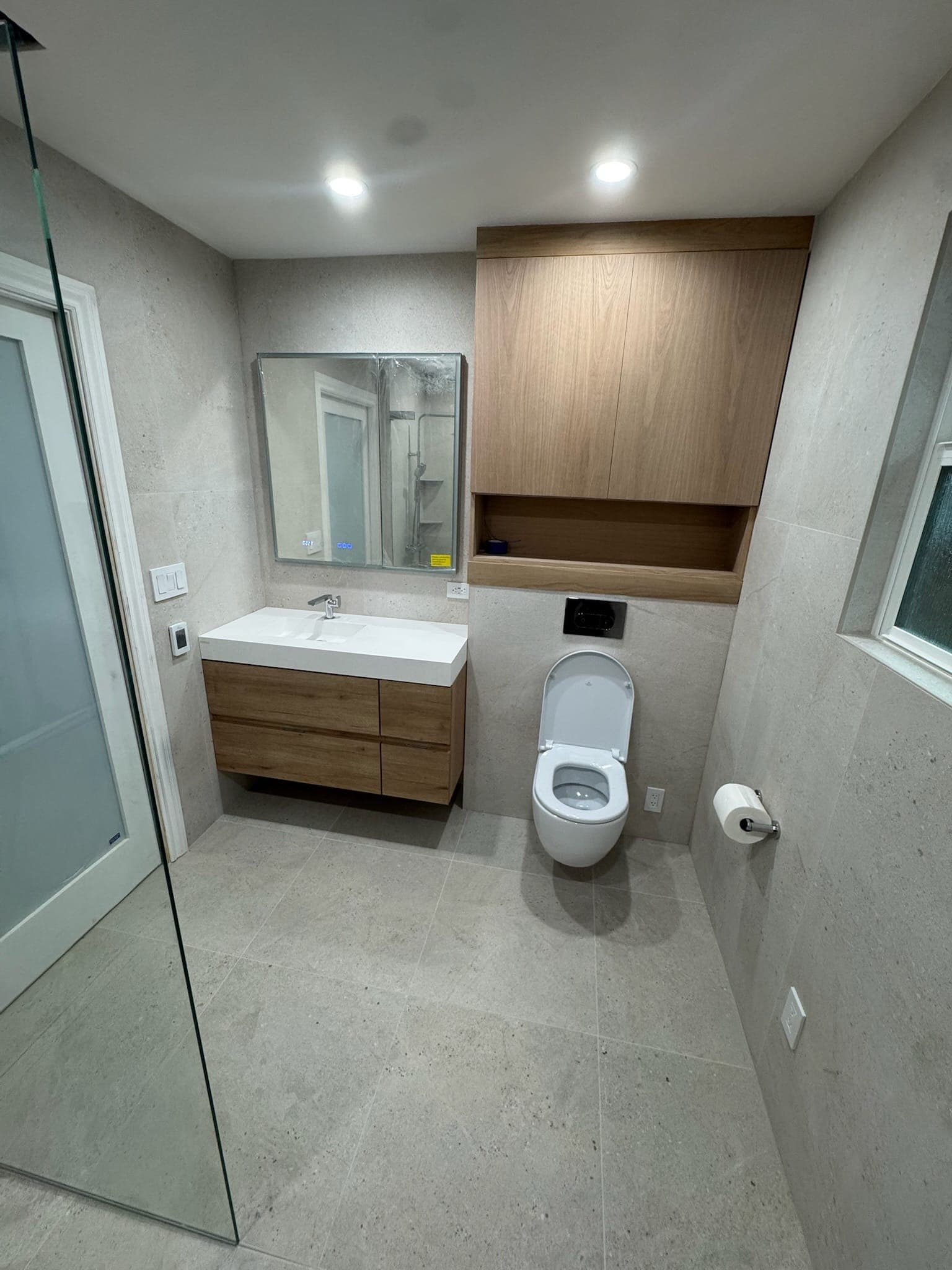 Finished bathroom with frosted pocket door, LED mirror cabinet, and wall-hung toilet