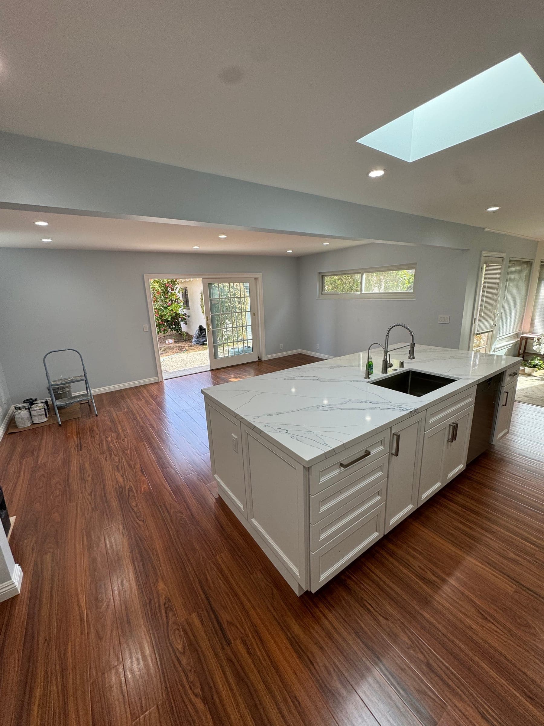 Quartz island with prep sink opening to the remodeled living and dining space