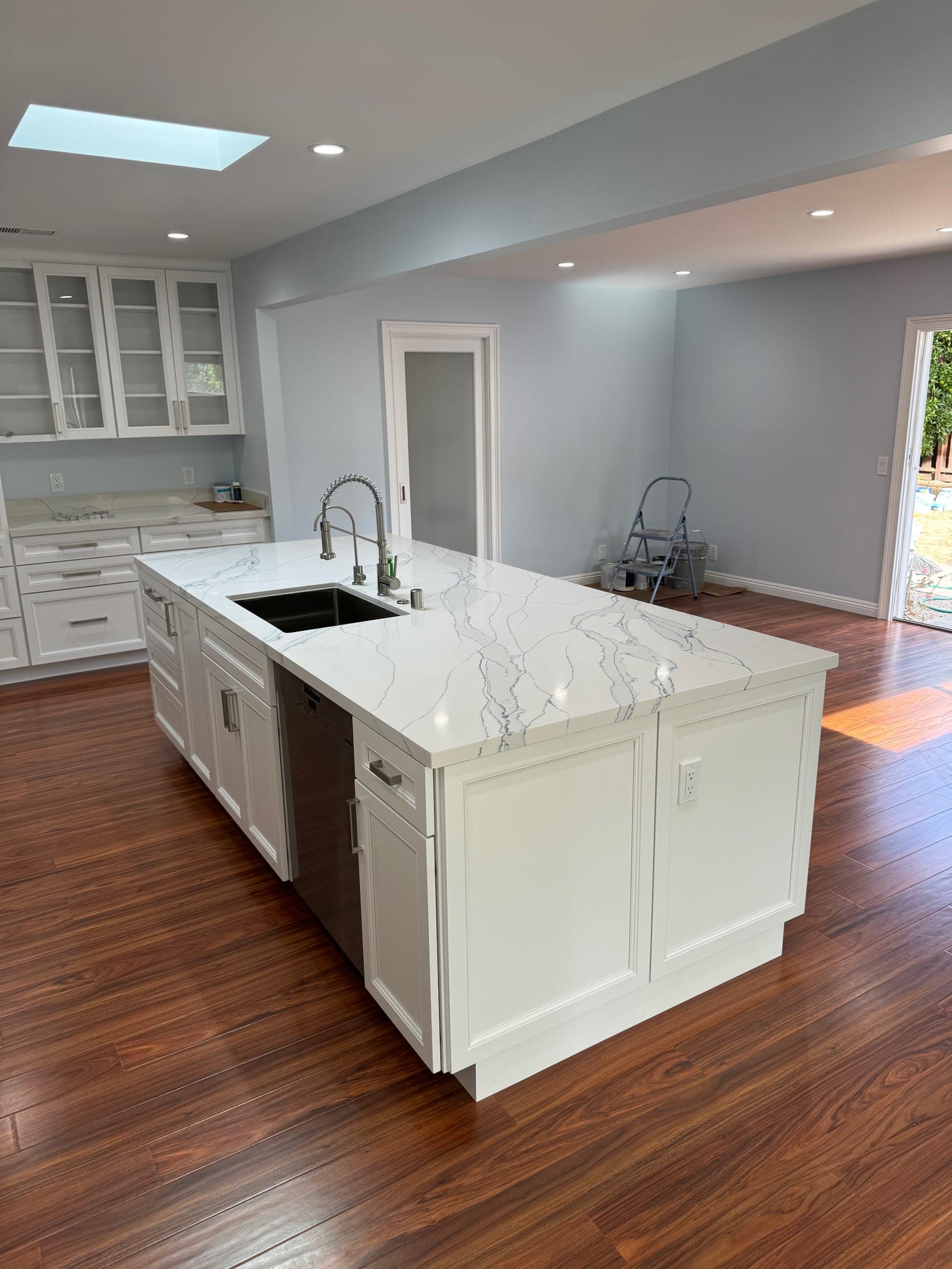 Kitchen island with veined quartz countertop and undermount sink in the opened-up room
